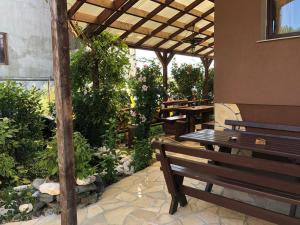 een patio met een houten bank en tafels en planten bij Pensiunea Tisa in Baile Felix