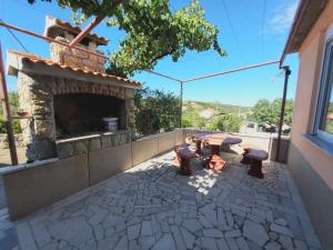 a patio with a fireplace and a table and benches at Apartment Maskarin Rab in Mundanije
