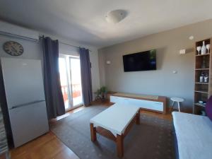 a living room with a table and a tv on the wall at Apartment Maskarin Rab in Mundanije