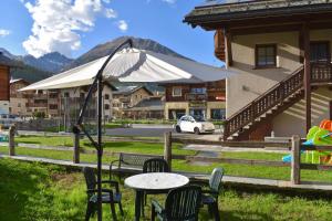 a table and chairs in front of a building with a tent at Appartamento 1 Baita Sosio Livigno in Livigno