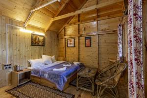Dormitorio de una cabaña de madera con cama y silla en Mid Conifer Cottage, en Dalhousie