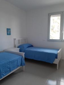 two beds in a white room with a window at Villa Marna Bianca in Borgo Bonsignore
