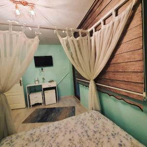 a bedroom with a bed with curtains and a television at BEYAZEV BUTİK OTEL MAŞUKİYE in Kartepe