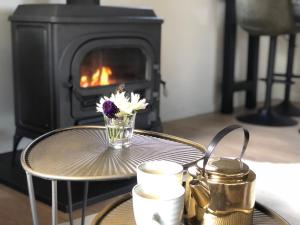 a table with a vase of flowers and a fireplace at Chalet aan de Rotte in Rotterdam