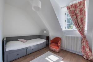 um quarto com uma cama, uma cadeira e uma janela em L'Annexe du Manoir - A proximité de Carantec em Taulé