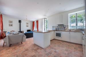 uma cozinha com armários brancos e uma mesa em L'Annexe du Manoir - A proximité de Carantec em Taulé