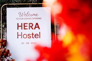 a sign for a herra hostel next to flowers at HERA HOSTEL in Chau Doc
