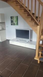 a living room with a flat screen tv and stairs at Schöne Maisonette Düren in Düren - Eifel
