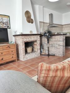 uma sala de estar com uma lareira de tijolos e uma televisão em El Jándalo em Benaocaz
