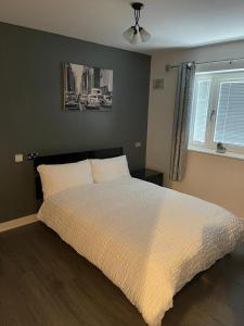 a bedroom with a bed with a white comforter and a window at Remarkable 2-Bed Apartment in Wolverhampton in Wolverhampton