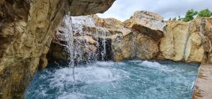 a plunge pool with a waterfall in a rock wall at Montenegro Royal 2 Bedroom Apartment in Bečići