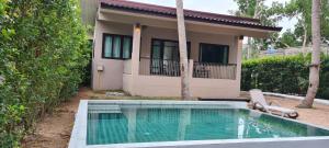 a house with a swimming pool in front of a house at Samutra Residences in Thong Sala