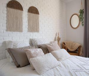 una camera bianca con un letto con cuscini sopra di Home By Sab 