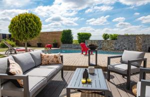 une terrasse avec un canapé et des chaises ainsi qu'une piscine dans l'établissement Home By Sab, 