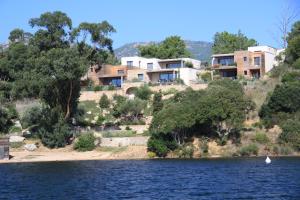 una casa en una colina junto a un cuerpo de agua en Résidence Affasciata, en Porto Vecchio