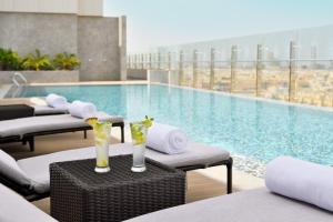- une piscine avec des chaises longues et des boissons sur une table dans l'établissement Crowne Plaza - Jeddah Al Salam, an IHG Hotel, à Djeddah