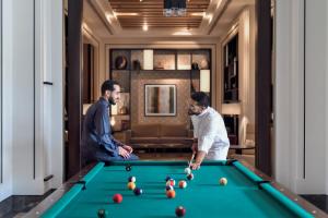 two men playing pool in a hotel room at Crowne Plaza - Jeddah Al Salam, an IHG Hotel in Jeddah