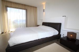 a bedroom with a bed with white sheets and a window at Résidence Affasciata in Porto-Vecchio