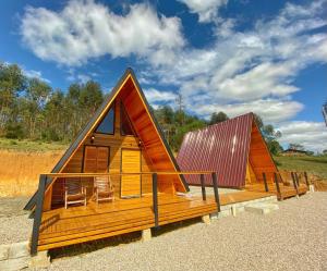 a cabin with a pitched roof and chairs on a beach at Pousada Sítio Elias - Chalé 1 in Lauro Müller