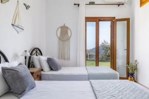two beds in a room with a window at Villa Chrysalis in Skopelos Town +52 photos