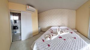 ein Schlafzimmer mit einem weißen Bett mit Rosen darauf in der Unterkunft Estalagem Vovô Elias in São Miguel dos Milagres