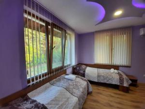 - une chambre avec 2 lits et une grande fenêtre dans l'établissement Райчевата къща - Кюстендил, à Kyustendil
