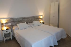 a bedroom with a large white bed with two pillows at Pension Campello The Blue Med in Alicante