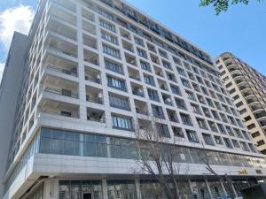 バクーにあるApartment near 28 Mallのバルコニーに人々がいる背の高い白い建物