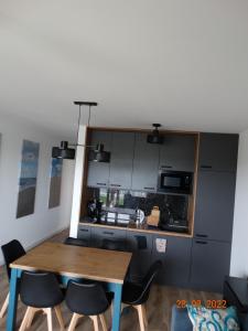 a kitchen with a wooden table and some chairs at Apartament na Piaskowej in Żarnowska