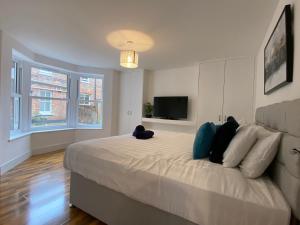 a bedroom with a large white bed with a flat screen tv at De Parys Self-Catering Flat 2 in Bedford in Bedford