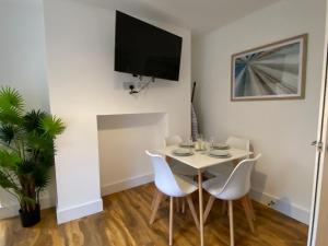 un pequeño comedor con una mesa y sillas blancas en De Parys Self-Catering Flat 2 in Bedford en Bedford