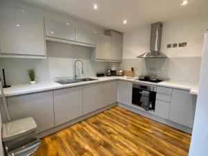 a kitchen with white cabinets and a wooden floor at De Parys Self-Catering Flat 2 in Bedford in Bedford