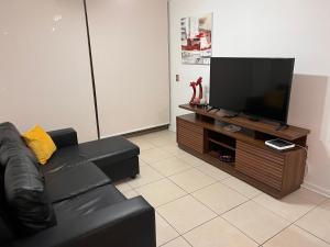 sala de estar con sofá negro y TV de pantalla plana en PuestadeSol,Apart en Iquique