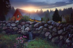 a stone wall with a waterfall in front of a house at Domek nad Czerwienią in Przesieka