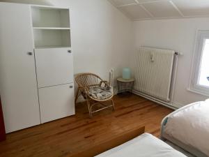 ein Schlafzimmer mit einem Stuhl und einem weißen Schrank in der Unterkunft Gîte les trois pierres, proche de Gérardmer in Liézey