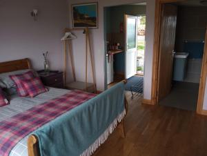 a bedroom with a bed with a plaid blanket on it at Seal Cottage in Portree