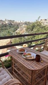 einen Holztisch mit Tellern aus Essen auf dem Balkon in der Unterkunft نزل حارة المسفاة Harit AL Misfah Inn in Misfāh