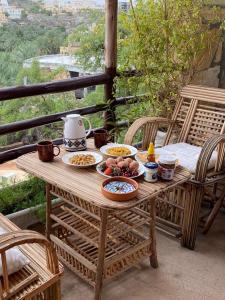 einen Holztisch mit Essschüsseln auf dem Balkon in der Unterkunft نزل حارة المسفاة Harit AL Misfah Inn in Misfāh
