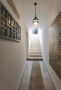 un pasillo con escaleras y una lámpara de araña en Ático Plaza 9 by casitasconencantoes en Medina Sidonia
