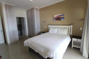 a bedroom with a large bed with white sheets and pillows at Saints View Resort Unit 23 in Uvongo Beach +23 photos