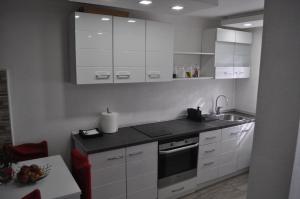 a kitchen with white cabinets and a sink at La Pausa suite Prijepolje in Prijepolje