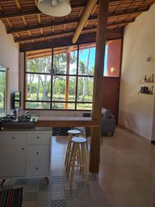 a kitchen with a table and stools in a room at Casa Terracota 2 - Beleza, conforto e sofisticação à 50m do rio in Caravellas