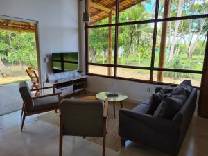 a living room with a couch and chairs and a table at Casa Terracota 2 - Beleza, conforto e sofisticação à 50m do rio in Caravellas