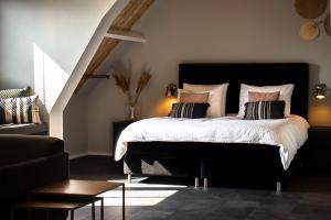 een slaapkamer met een groot bed met witte lakens en kussens bij Appartement de Hoge Stoep in Hollum