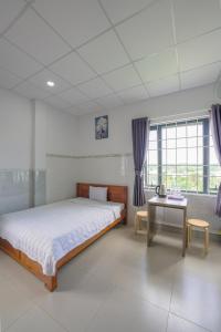 a bedroom with a bed and a desk and window at Thanh Ngoc Motel 2 in Buon Ma Thuot
