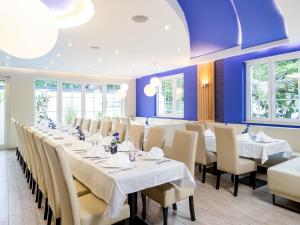 a large dining room with white tables and chairs at Kristallhotel Fettehenne in Leverkusen