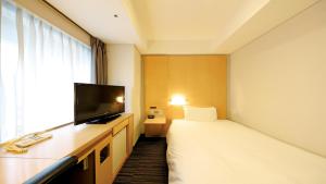 a hotel room with a bed and a flat screen tv at Smile Hotel Osaka Yotsubashi in Osaka
