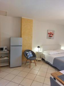 a bedroom with a bed and a chair and a refrigerator at Casa Panorama Studio in Rabac