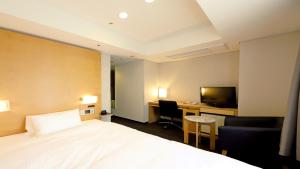 大阪市にあるスマイルホテル大阪四ツ橋のベッド、デスク、テレビが備わるホテルルームです。