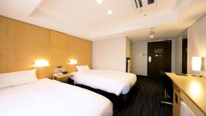 大阪市にあるスマイルホテル大阪四ツ橋のベッド2台とテレビが備わるホテルルームです。